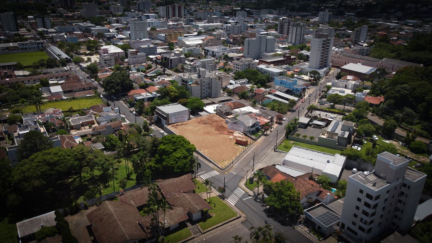 Vista aérea de terreno vazio de esquina no centro de Taquara, cercado por prédios e ruas asfaltadas